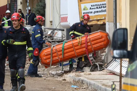 Άνδρες της ΕΜΑΚ μεταφέρουν φορείο για τους νεκρούς στο κτήριο της Πλάκας που έγινε έκρηξη