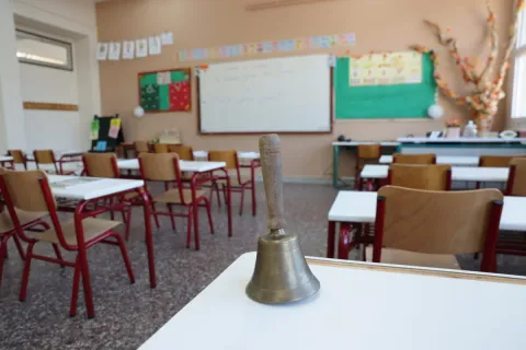 Τάξη σχολείου με κουδούνι πάνω σε θρανίο