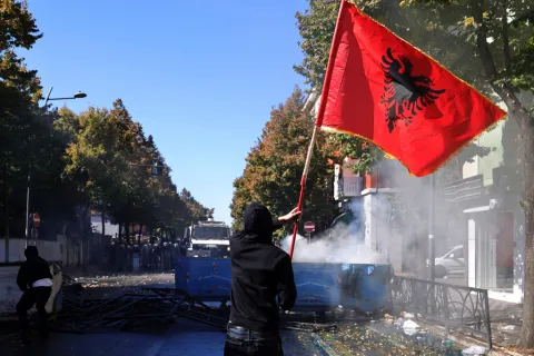 A protester waves an Albanian flag during clashes in Tirana, Albania, Wednesday, Oct. 14, 2026, joining a demonstration organized by the Flamingo protest movement demanding the resignation of Prime Minister Edi Rama. (AP Photo/Hameraldi Agolli)