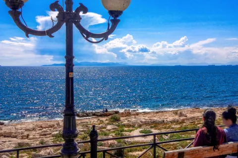 Γυναίκες κάθονται σε παγκάκι σε παραλία με καλό καιρό τον χειμώνα