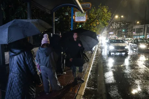 Κόσμος με ομπρέλες σε στάση λεωφορείου στην Αττική ενώ ειναι καταιγίδα σε ελέλιξη
